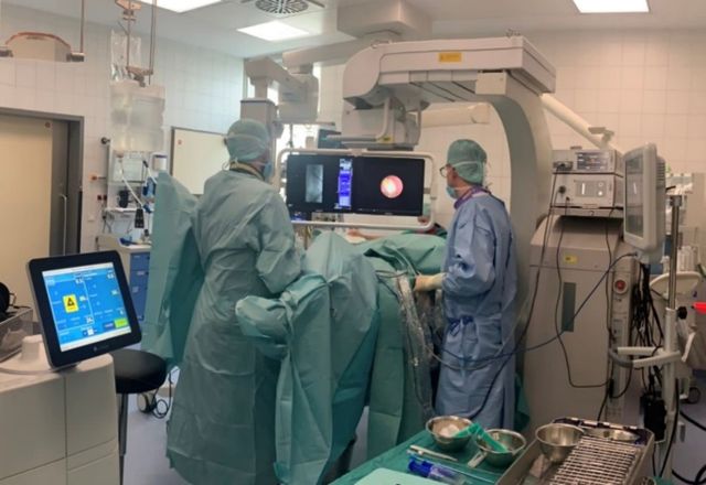 Abb. 2: ECIRS mit Operateur für URS zwischen den Beinen und Operateur für PNL an der linken Flanke. Beachte den separaten Monitor rechts im Bild für den URS-Operateur.