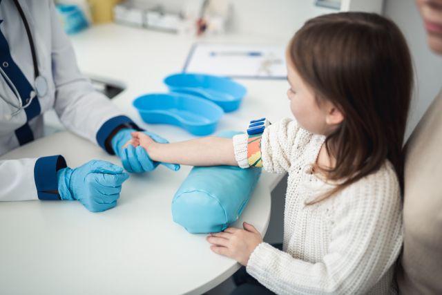 Arzt bereitet kleines Mädchen auf die Blutentnahme vor