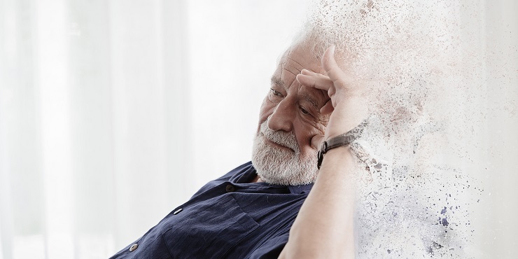 Symbolbild, älterer Mann sitzt in einem Stuhl und greift sich an dem Kopf. Der rechte Bildteil löst sich in kleine Teile auf.