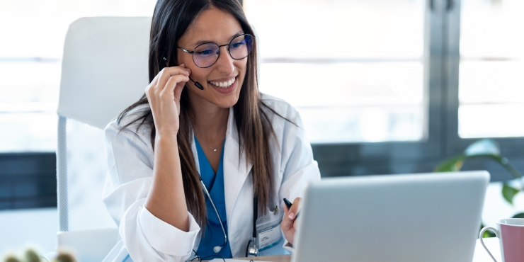 Symbolbild, Ärztin sitzt mit Headset am Laptop