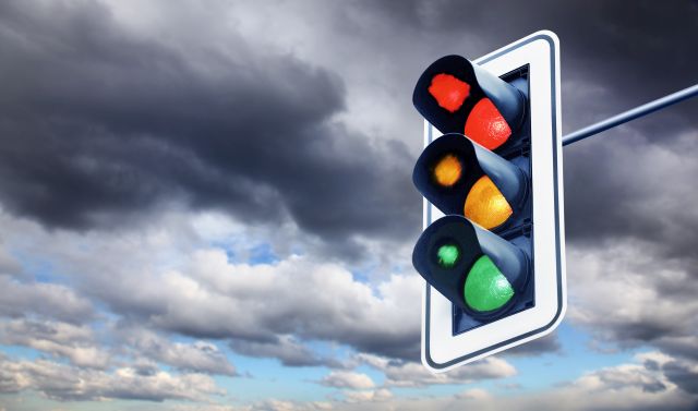 Ampel mit allen Farbphasen leuchtend, vor dunklen Wolken