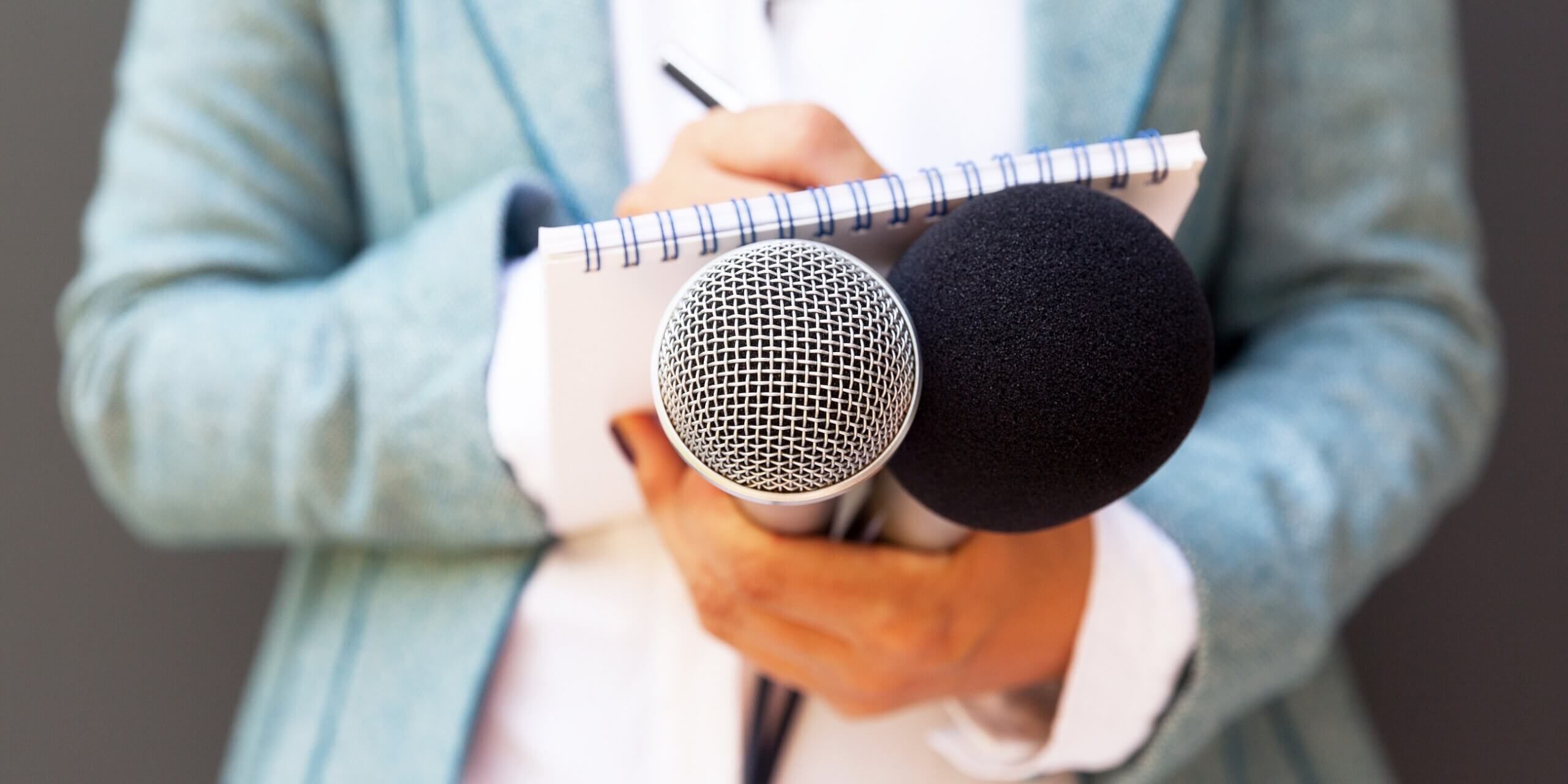 Symbolbild für ein Interview, Hände einer Journalistin halten Schreibblock Stift und Mikrofon