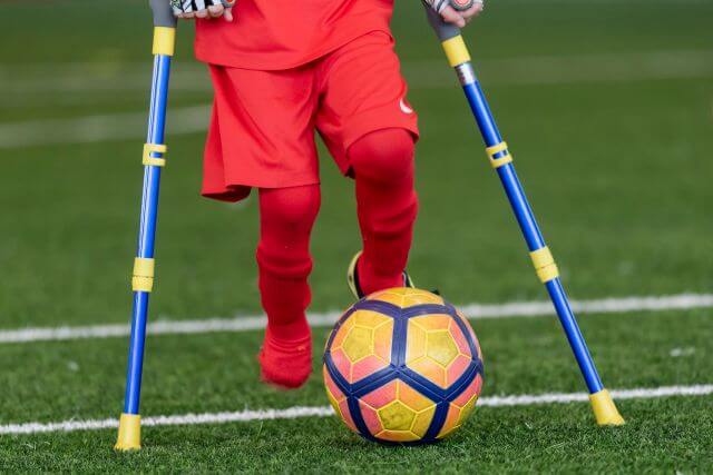 Behinderter Fußballspieler mit Krücken