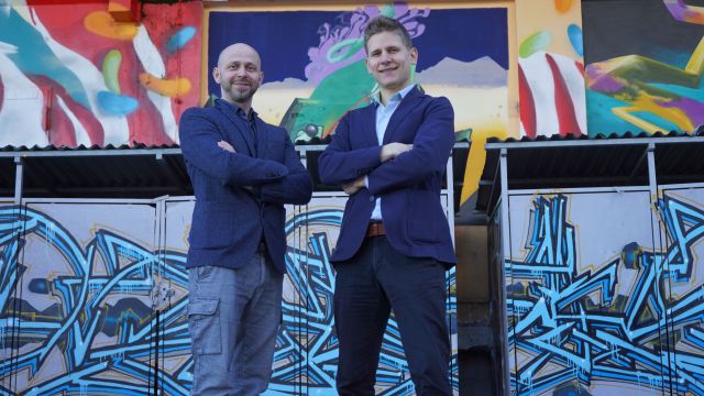 Ratko Petrovic und Manuel Opitz stehen vor einer Graffitiwand