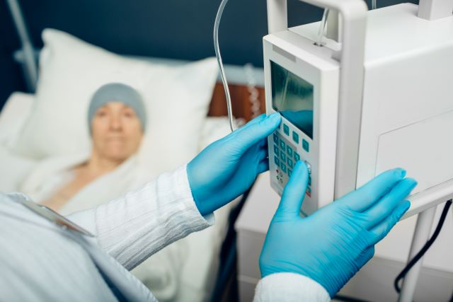 Nahaufnahme einer Infusionspumpe, die von medizinischem Personal mit Handschuhen eingestellt wird