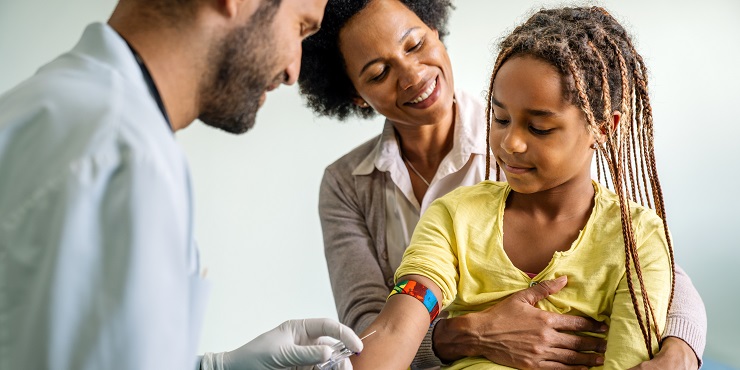 Symbolbild, Blutabnahme bei einem Mädchen, das auf dem Schoß ihrer Mutter sitzt.