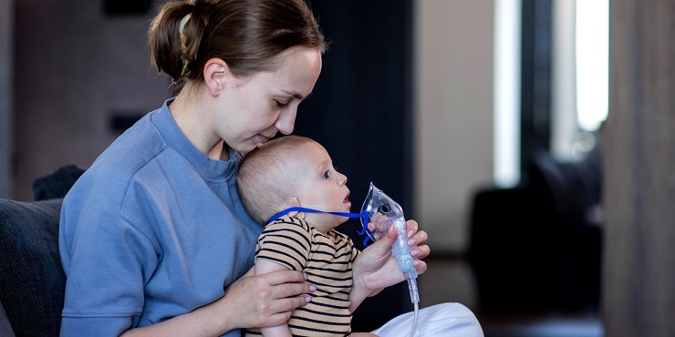 Mutter setzt Baby eine Inhalationsmaske auf