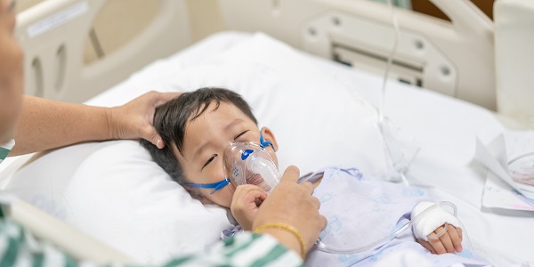 Kind liegt in einem Kranknausbett und wird beatmet