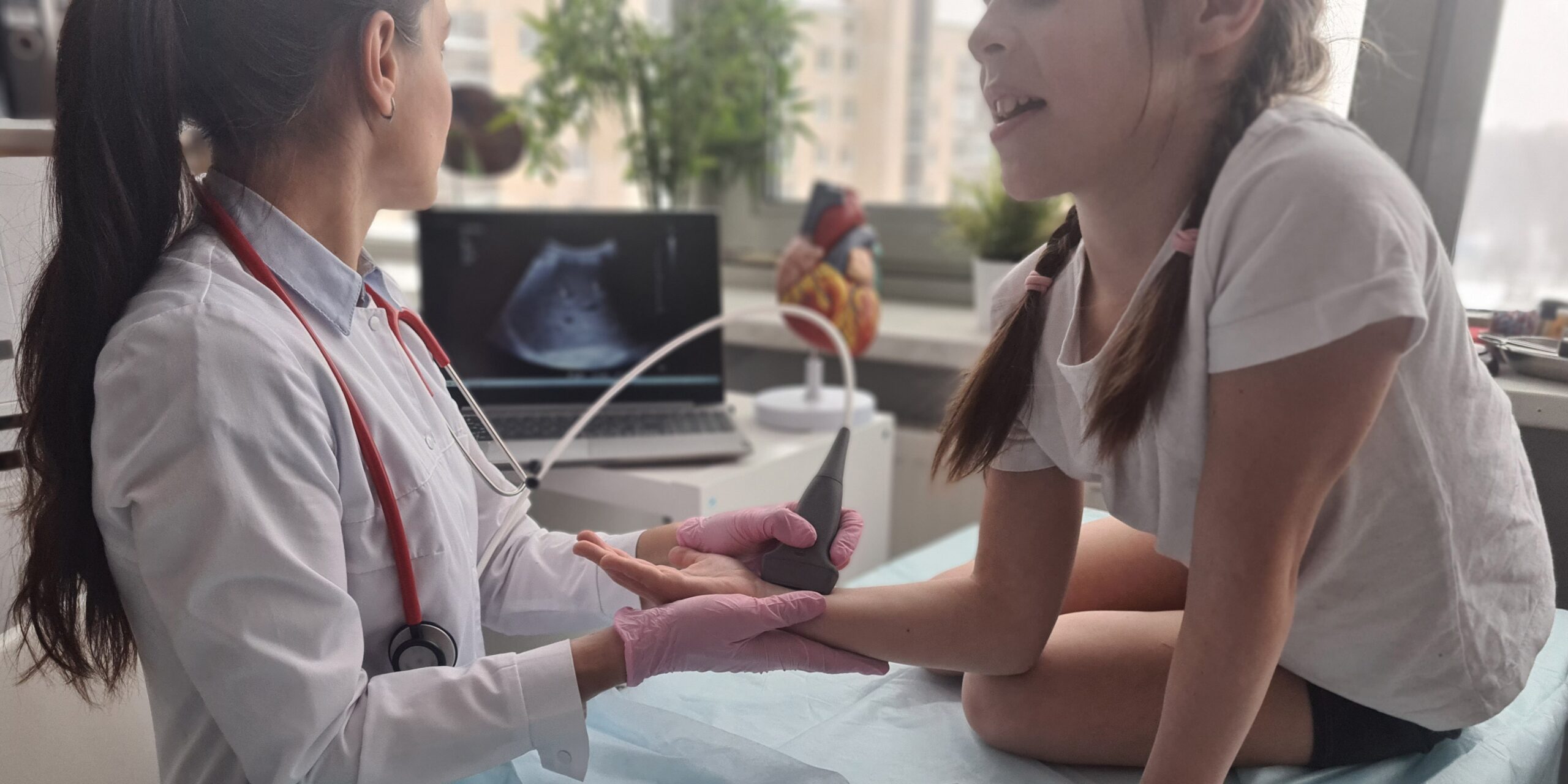 Eine Ärztin untersucht das Handgelenk eines Kindes mittels Ultraschall