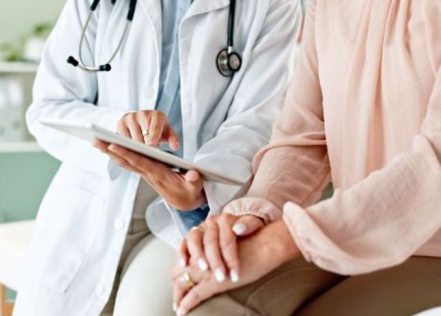 Ärztin zeigt Patientin medizinische Informationen auf einem Tablet in einer Praxis.