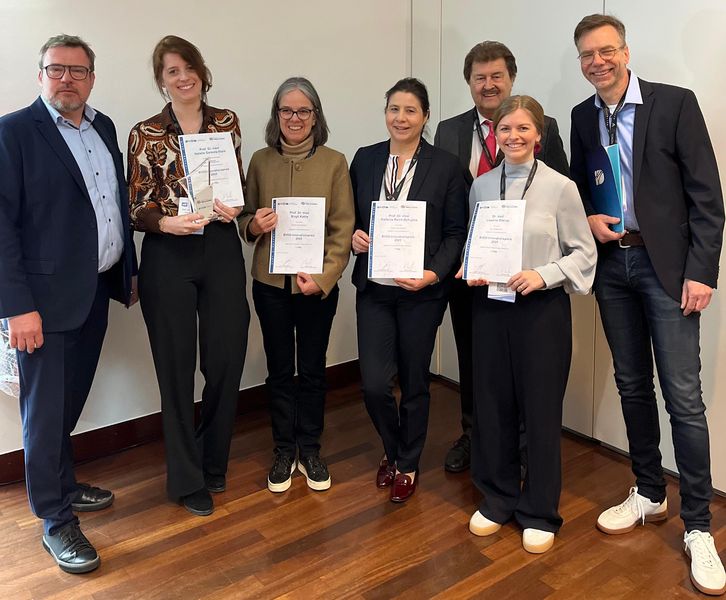 Eine Gruppe von Personen hält Urkunden in einem Veranstaltungsraum nach einer Auszeichnung.