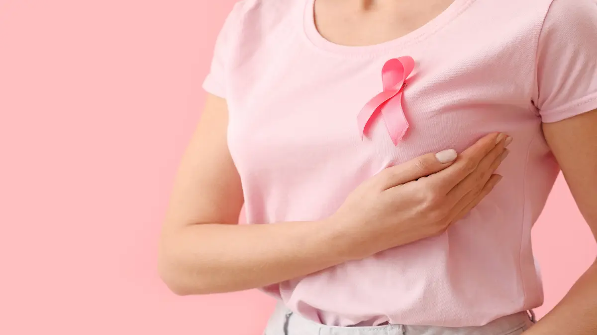 Eine Frau trägt ein rosa T-Shirt mit der bekannten rosa Schleife – dem Symbol für Brustkrebsbewusstsein