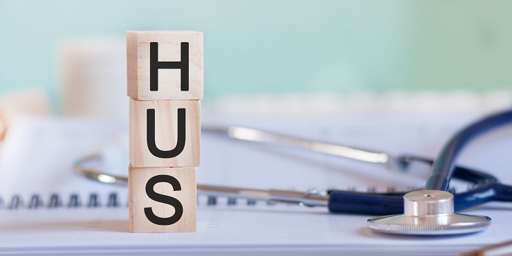 Holzwürfel mit Buchstaben "HUS", daneben ein Stethoskop