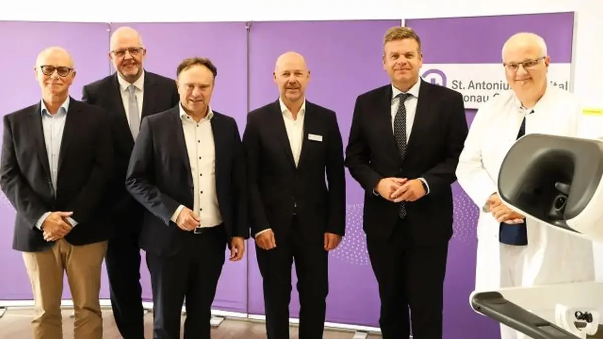 Neben der Konsole des Gronauer da Vinci-5-Operationssystems stehen (v.l.) Patient Bernd Loeffler, Intuitive Senior Vice President Dirk Barten, Landrat Dr. Kai Zwicker, Christoph Bröcker (Geschäftsführer St. Antonius Hospital), NRW-Staatssekretär Matthias Heidmeier sowie Chefarzt Dr. Christian Wagner. (Foto: St. Antonius Hospital Gronau)