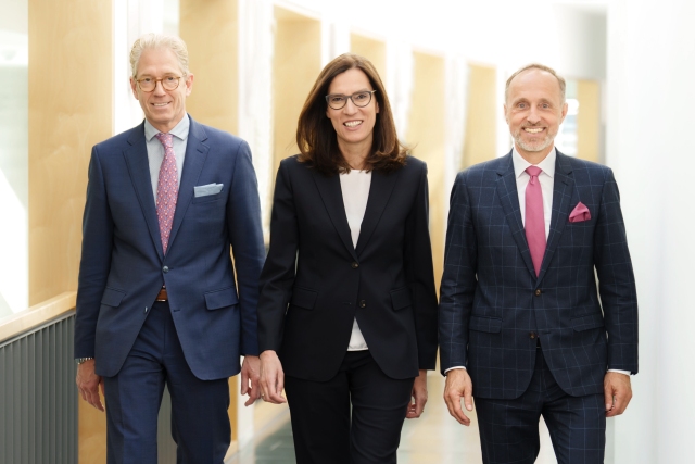 Die KBV-Vorstände Dr. Andreas Gassen, Dr. Sibylle Steiner und Dr. Stephan Hofmeister in einem modernen Büroflur.