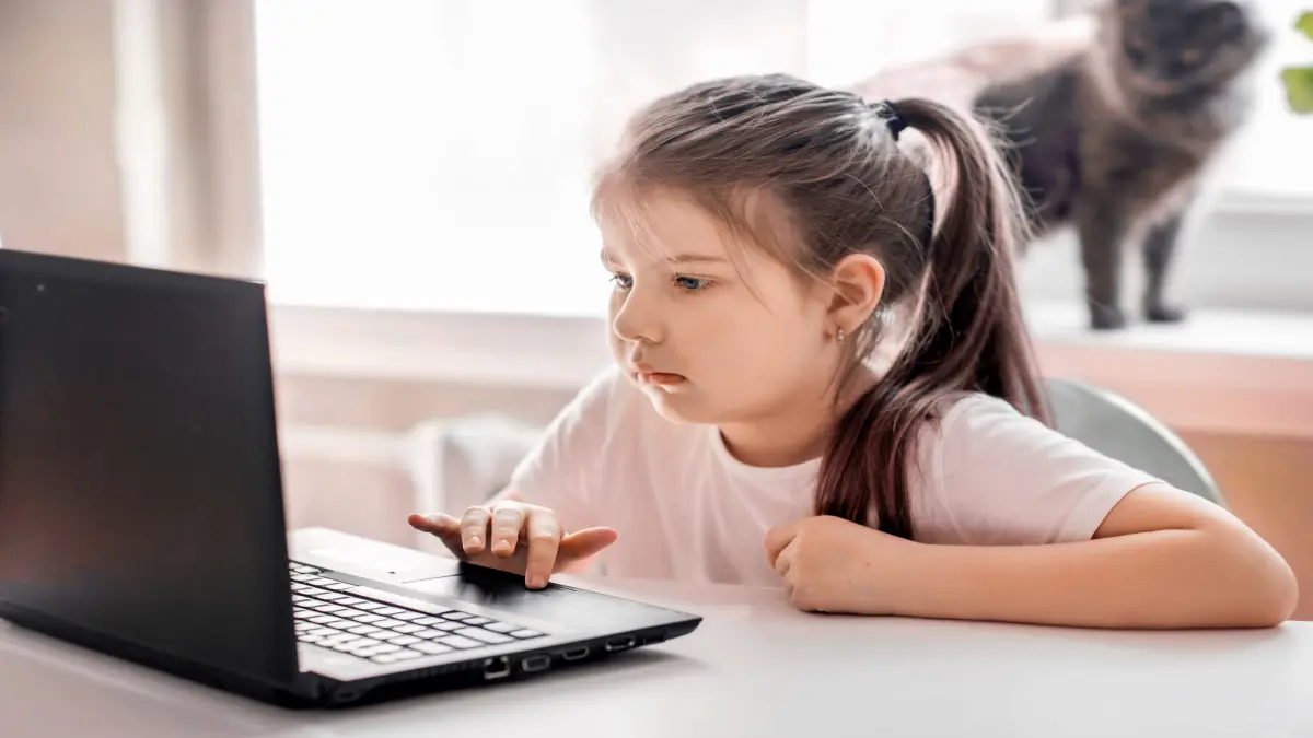 sad little girl sitting at the computer