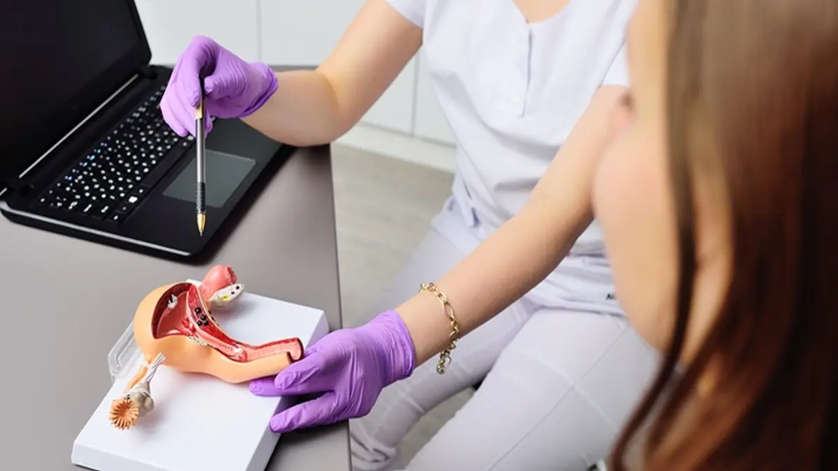 Gynäkologin berät eine Jugendlichen und zeigt auf ein anatomisches Modell eines Uterus