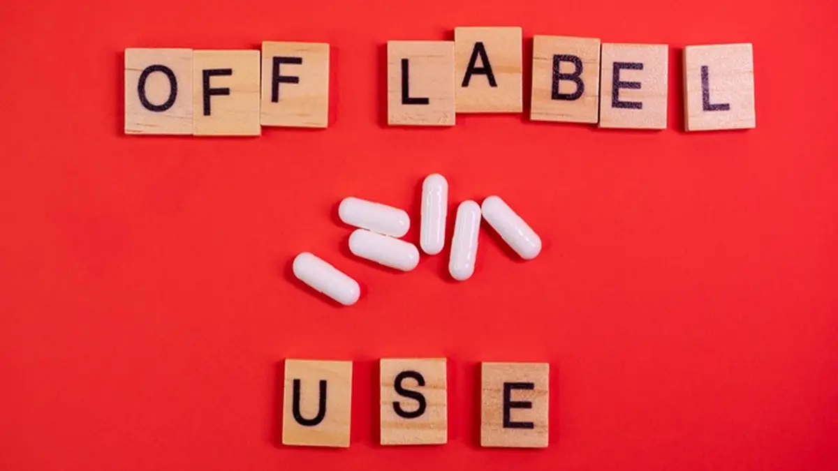 Buchstaben des "Off Label Use" aus Holz, dazwischen weiße Pillen