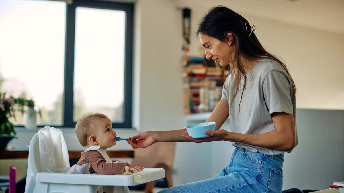 Mutter füttert ihr Kind, symbolisiert die frühzeitige Einführung von allergenen Nahrungsmitteln wie Erdnüssen und Eiern zur Prävention von Nahrungsmittelallergien.