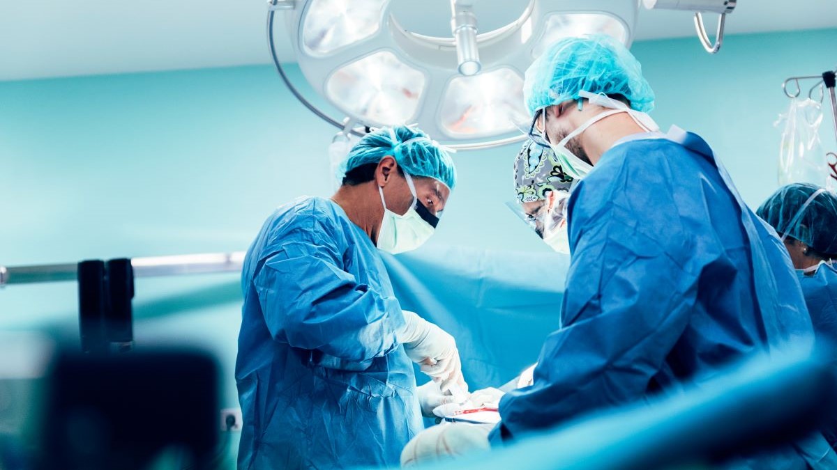 Chirurgen bei einer Operation im sterilen Operationssaal unter OP-Lichtern.