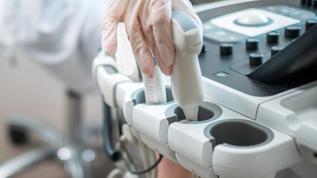 Nahaufnahme einer Hand, die auf einem Ultraschallgerät liegt. Symbolbild zur sonografischen Untersuchung