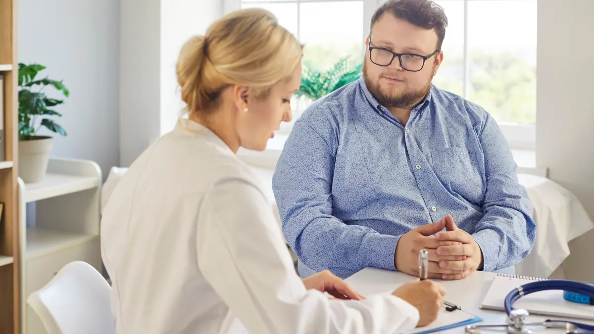 Ärztin unterhält sich mit einem übergewichtigen jungen Mann über Testergebnisse