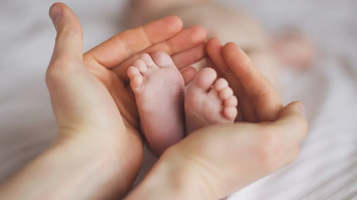 Geburtshilfe international: Hände schützen Babyfüße, Symbol für Verbesserung.